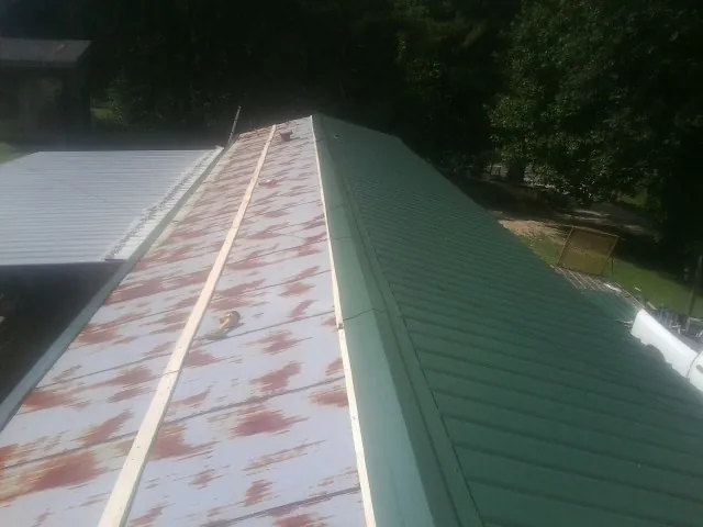 Old rusted panels beside newly installed green metal roofing — Wind Damage Roof Repair by Roofing Brothers in Ovid